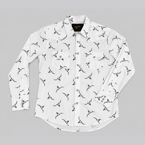 A white long-sleeve button-up shirt with an all-over black bird print, laid flat on a neutral gray background.