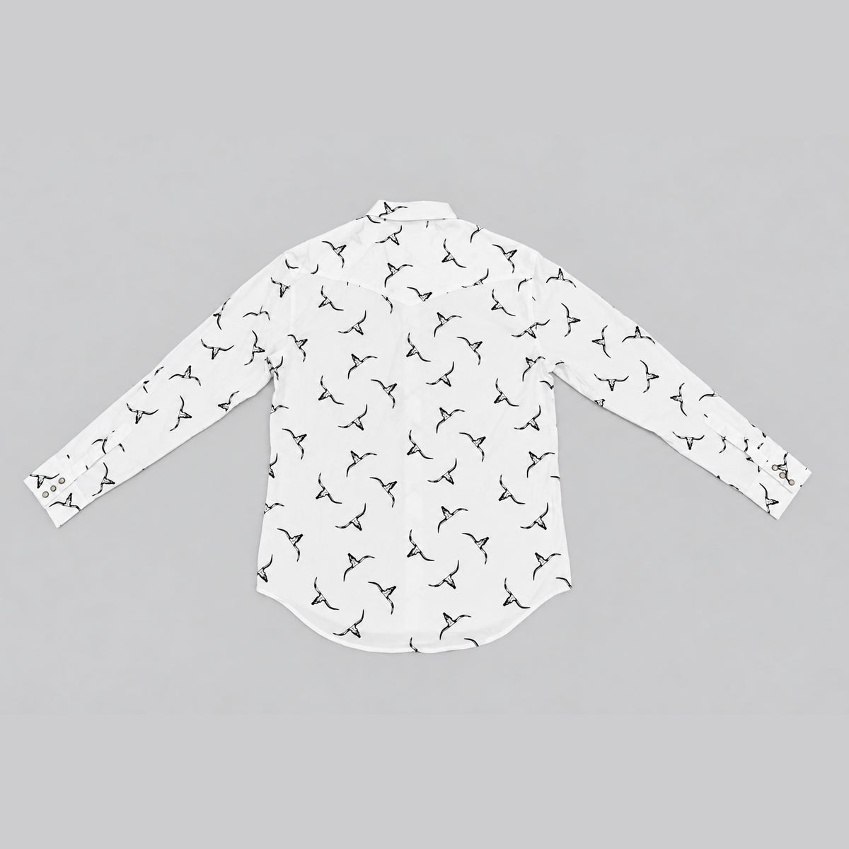 A white long-sleeve button-up shirt with an all-over Thrivin' Here Co. icon print, laid flat against a solid gray background.